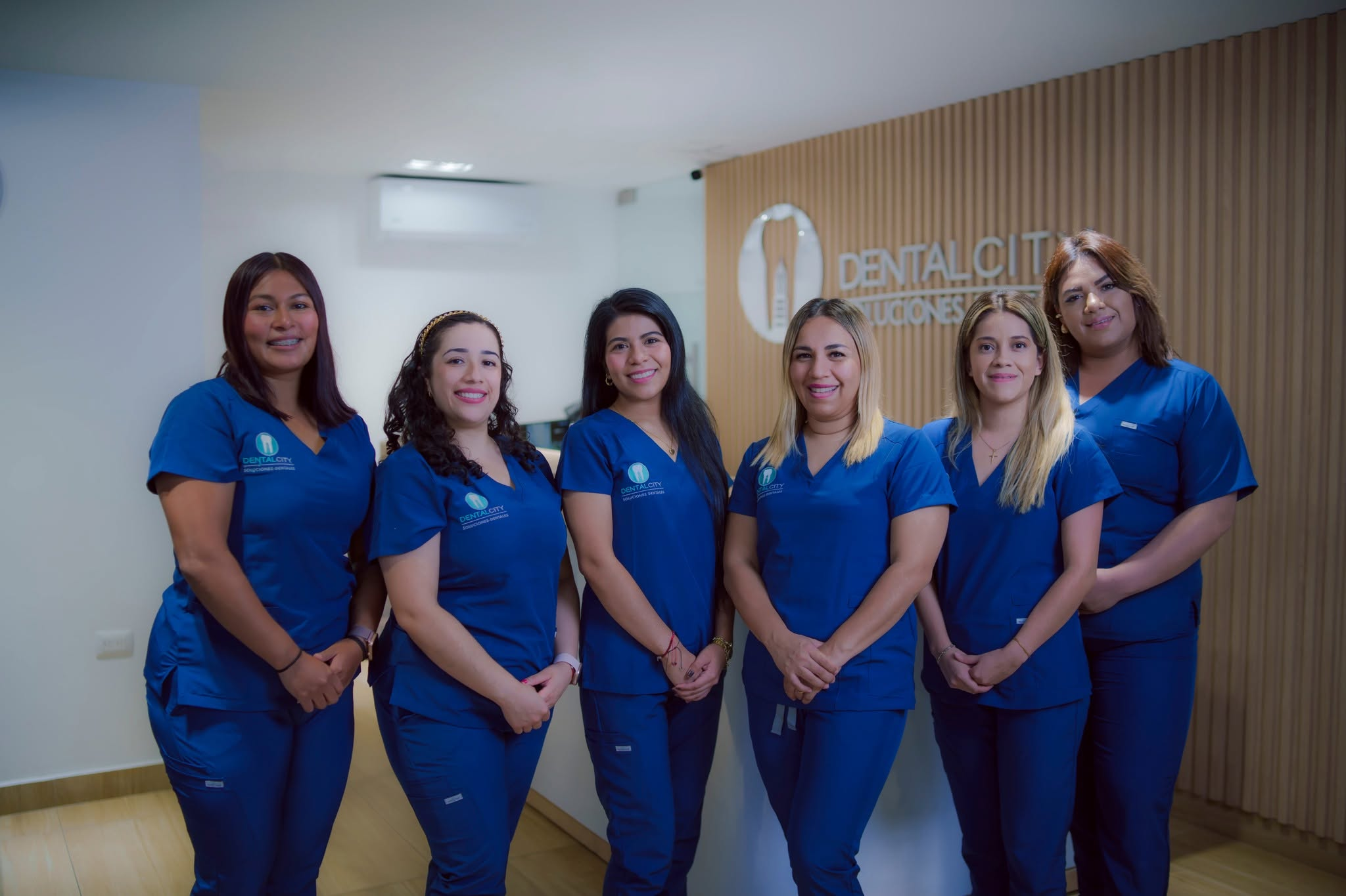 Equipo real de Dental City con uniformes azules en la clínica
